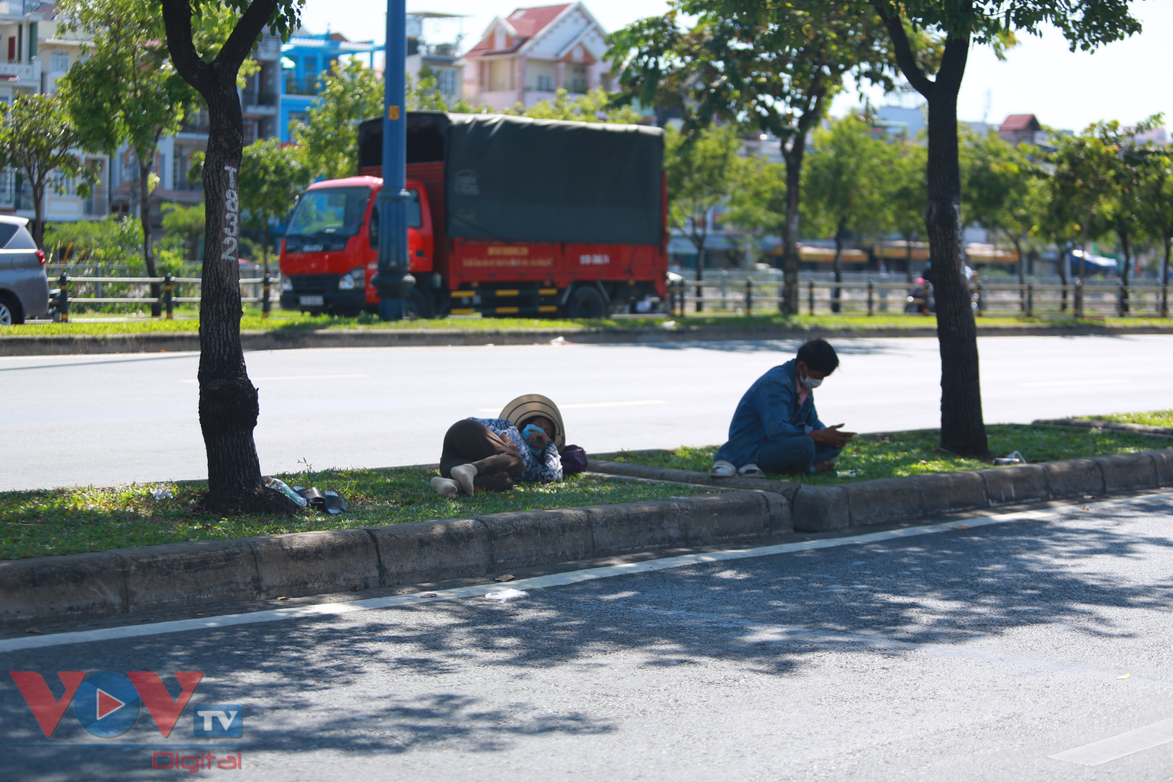 Nắng nóng, một vài người lao động tránh nắng dưới các tán cây dọc đường.jpg