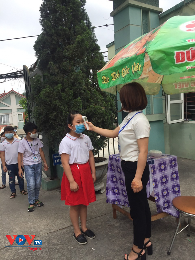 Cán bộ y tế kiểm tra thân nhiệt cho học sinh trường Tiểu học Cao Xanh thành phố Hạ Long